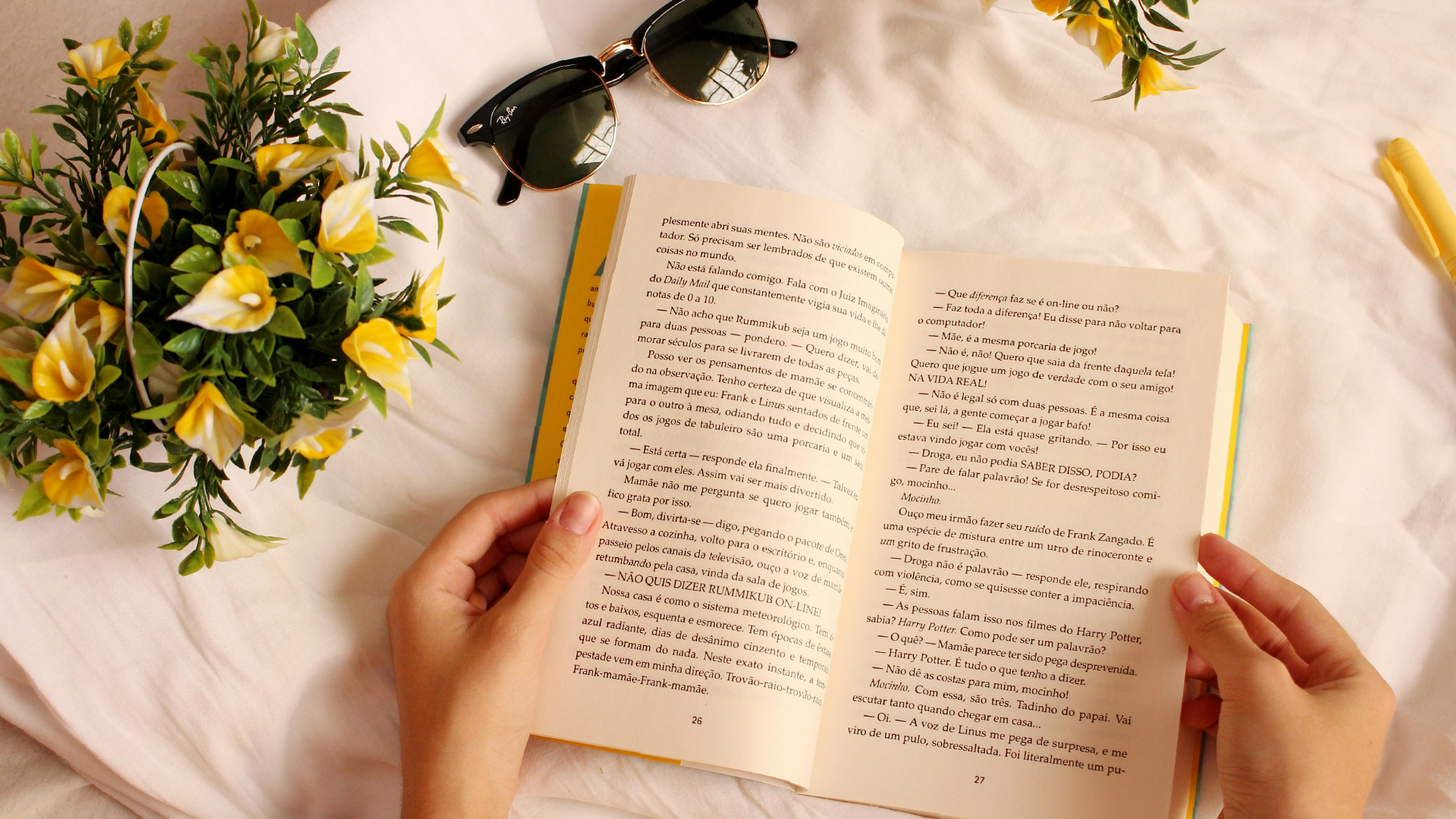 Person reading a book with yellow flowers surrounding it.